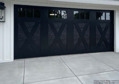 This image shows Clopay Canyon Ridge CAN221UG garage doors in mahogany, with a sleek black finish and clear glass panels