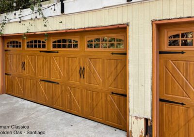 Rustic Amarr garage doors in Golden Oak finish with decorative windows and carriage-style hardware on cream exterior.